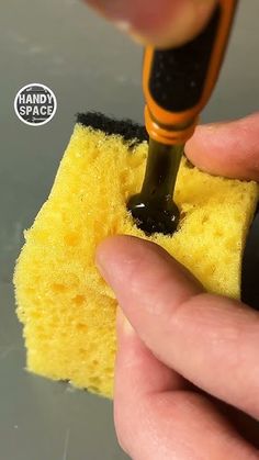 a person is using a sponge to clean the floor with a small yellow item in their hand