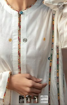 a woman wearing a white shirt with colorful beads on the collar and sleeves is holding her hand to her ear