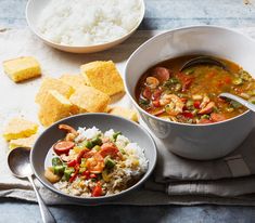 two bowls filled with soup and rice next to some crackers on a tablecloth