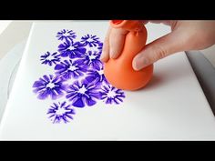 someone is using an orange rubber stamp to decorate flowers on a piece of white paper