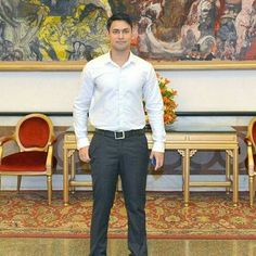 a man standing in front of a large painting with chairs around him and his hands in his pockets