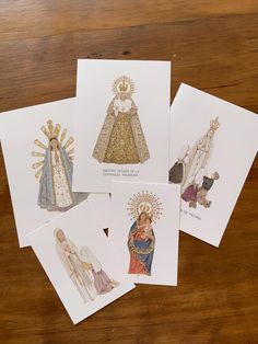 four cards with images of the virgin mary and baby jesus on them, sitting on a wooden surface