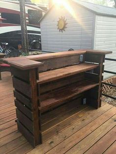 a wooden table sitting on top of a wooden deck next to a white building with a sun shining through the window