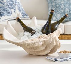 three bottles of beer sitting in a bowl on top of a table next to some ice cubes