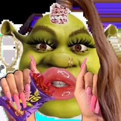 a woman with green makeup and pink nails holding a candy bar in front of her face