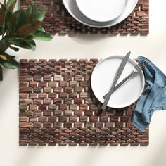 two placemats with white plates and silverware on them next to a potted plant