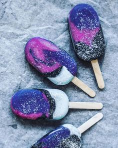 four popsicles covered in purple and black sprinkles