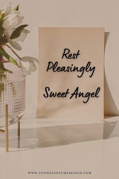 a sign that says rest pleasingly sweet angel next to a vase with white flowers