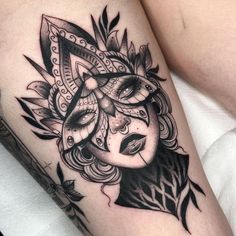 a woman's thigh with a mask and feathers tattoo design on it, as well as an arrow