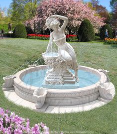 there is a fountain with a woman holding a basket on it in the middle of a park