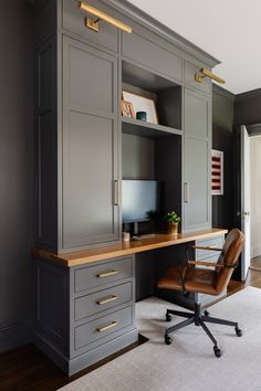 an office with gray cabinets and a brown leather chair in front of the computer desk