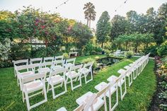 rows of white chairs set up in the middle of a garden with water and trees