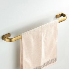 a gold towel rack with two towels hanging from it's sides and a white wall in the background