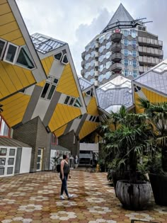 a person is walking in the middle of an outdoor area with plants and buildings behind them