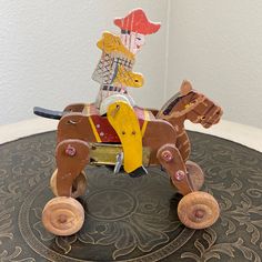 a wooden toy horse with a man riding on it's back sitting on top of a table