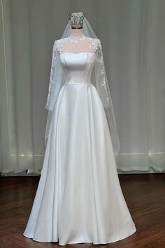 a white wedding gown on display in front of a curtain with a tiara and veil