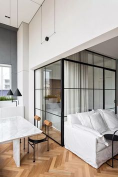 a living room filled with furniture and a white table in front of a glass wall