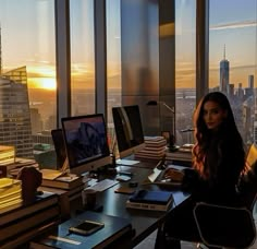 a woman sitting at a desk in front of a window with a view of the city