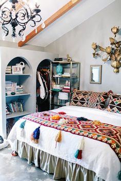 a room with a bed, bookshelf and various items on the shelves in it