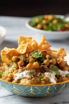 a bowl filled with food sitting on top of a table next to bowls of chips