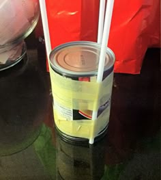 two white straws sticking out of a can on top of a black table next to a red bag