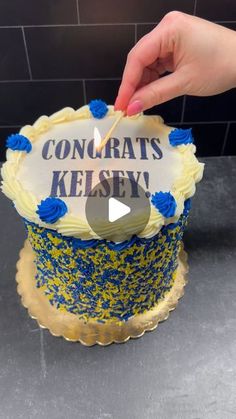 someone is decorating a cake with blue and yellow sprinkles on it