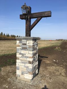 a large wooden cross sitting on top of a stone block pillar in the middle of a field