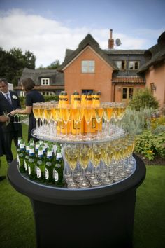 there are many glasses on the table with drinks in them and people standing around it