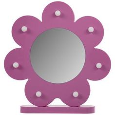 a pink flower shaped mirror sitting on top of a wooden stand