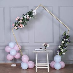 balloons, flowers and greenery are arranged on the floor in front of a white table