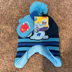 a blue hat with an animal on it sitting on the floor next to a book