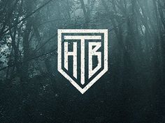 the hbc logo is surrounded by trees in the foggy forest, and it appears to be white