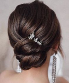 the back of a woman's head with hair combs in her hair and earrings