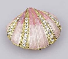 a pink and gold shell shaped brooch with crystal stones on it's sides