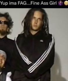 two men with long hair and sunglasses standing next to each other in front of a white wall