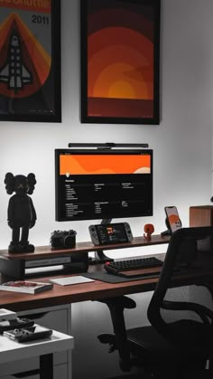 a desk with a computer monitor, keyboard and mouse on it in front of two framed pictures