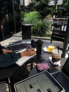 a woman sitting at a table with two laptops and a tablet on her lap