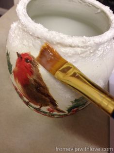 a paintbrush sitting on top of a white vase with a bird painted on it