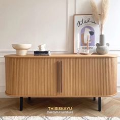 a wooden cabinet with two vases on top of it next to a framed photograph