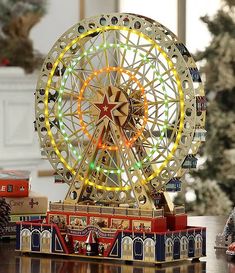 a toy ferris wheel sitting on top of a wooden table next to a christmas tree