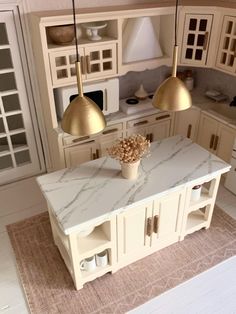 a model kitchen with marble counter tops and gold pendant lights hanging from the ceiling over the island