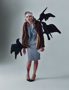 a woman in a gray dress and some black birds