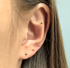 a close up of a person's ear with three different colored stones on it