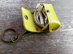 a yellow leather case with earbuds in it sitting on a wooden table next to a key chain