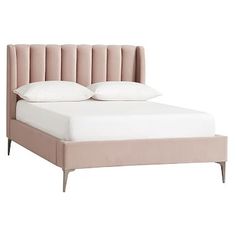 an upholstered bed with two pillows on it