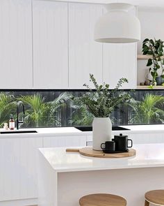 a kitchen with two stools next to a counter top and potted plants on the window sill