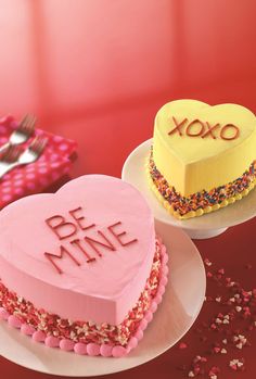 two heart shaped cakes on plates with the words xoxo and be mine written on them