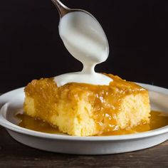 a spoon drizzling caramel sauce onto a piece of cake on a white plate