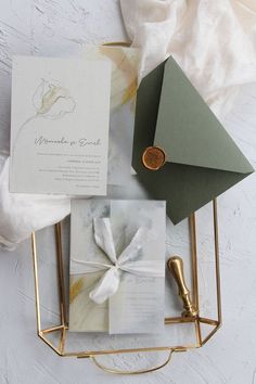 the wedding stationery is laid out on top of a gold wire holder with a wax stamp