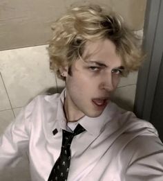 a young man with blonde hair wearing a white shirt and black tie, posing for the camera